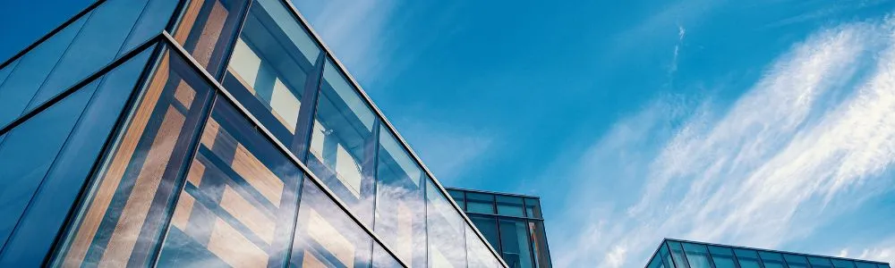 青空を背景にそびえるガラス張りのビル