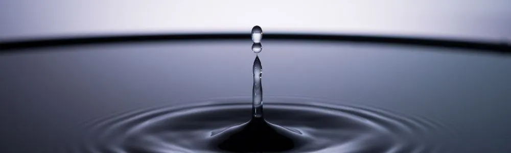 暗い灰色の水面に落ちる水滴