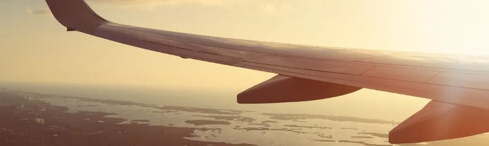 大空を飛ぶ飛行機の翼の写真